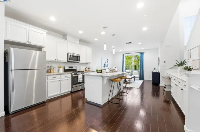 a kitchen with a refrigerator a stove top oven a sink dishwasher and white cabinets with wooden floor