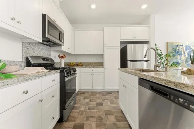 a kitchen with granite countertop a sink stove and cabinets