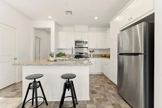 a kitchen with stainless steel appliances granite countertop a refrigerator and a stove top oven