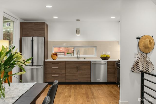 a kitchen with stainless steel appliances kitchen island granite countertop a refrigerator a stove and a wooden floors