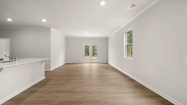 a view of an empty room with window and wooden floor