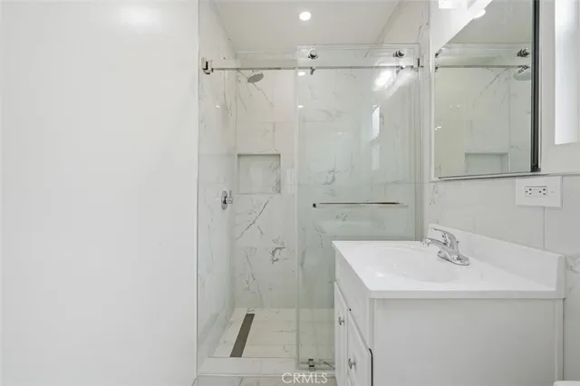 a bathroom with a sink a glass door shower and a mirror