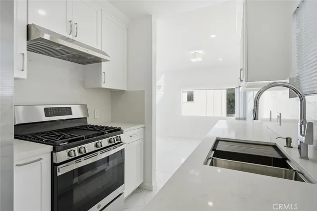 a kitchen with granite countertop a stove and a white cabinets
