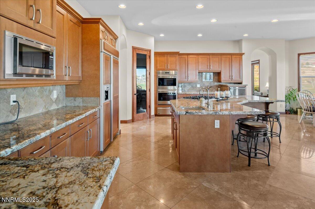 13005 Silver Wolf Road Reno, NV 89511 - Photo 20 of 40 a large dining hall with stainless steel appliances granite countertop a stove a sink a dining table and chairs