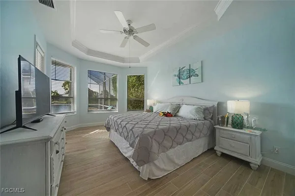 a bedroom with a bed wooden floor and large window