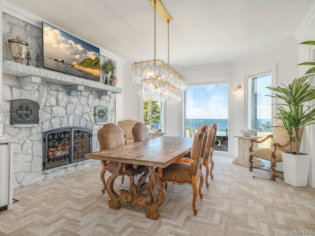 3875 Hallock Lane Mattituck, NY 11952 - Photo 14 of 50 Dining area featuring a fireplace, crown molding, plenty of natural light, and a chandelier