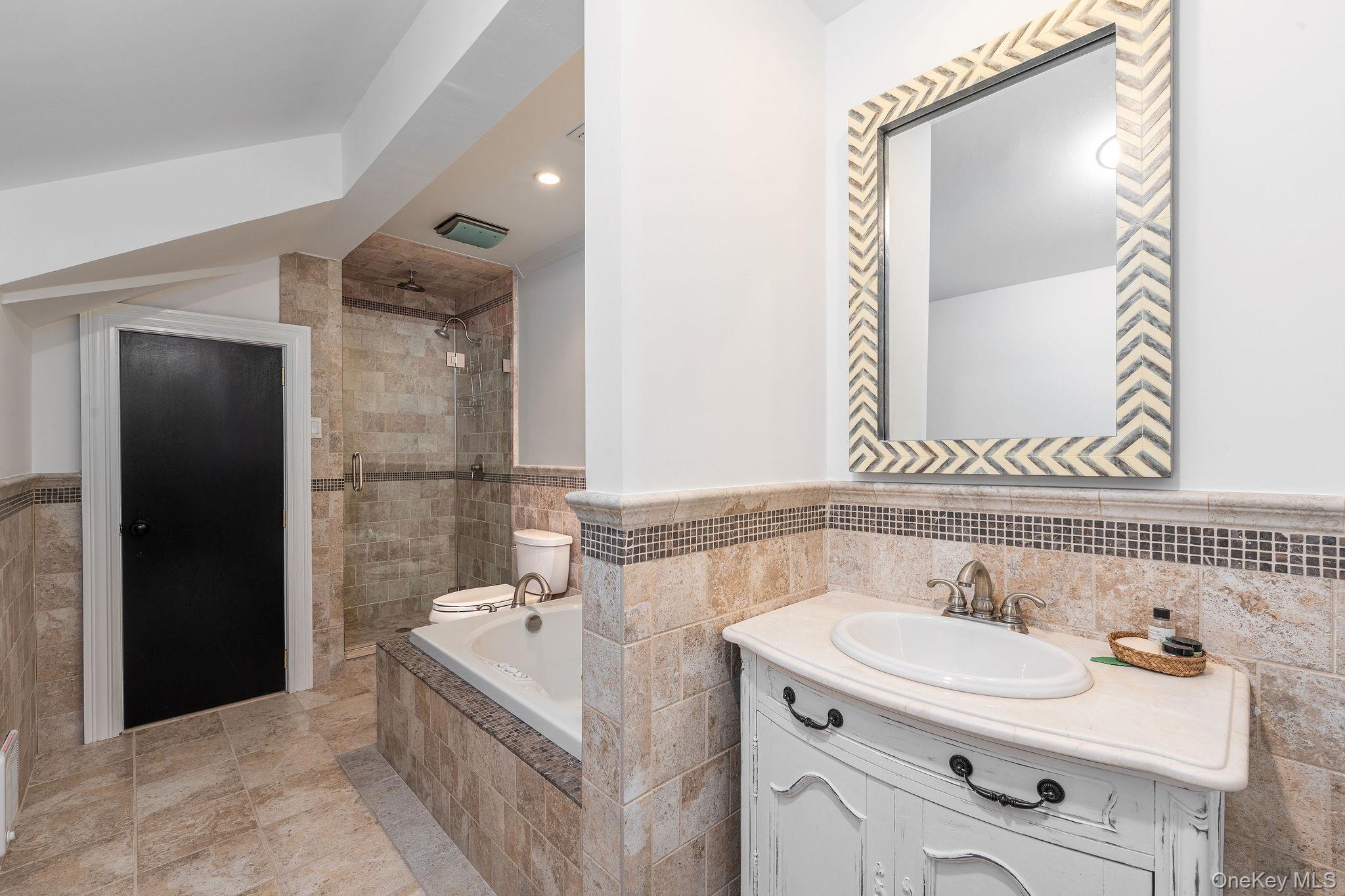 3875 Hallock Lane Mattituck, NY 11952 - Photo 24 of 50 Bathroom with tile walls, vanity, wainscoting, a stall shower, and a bath