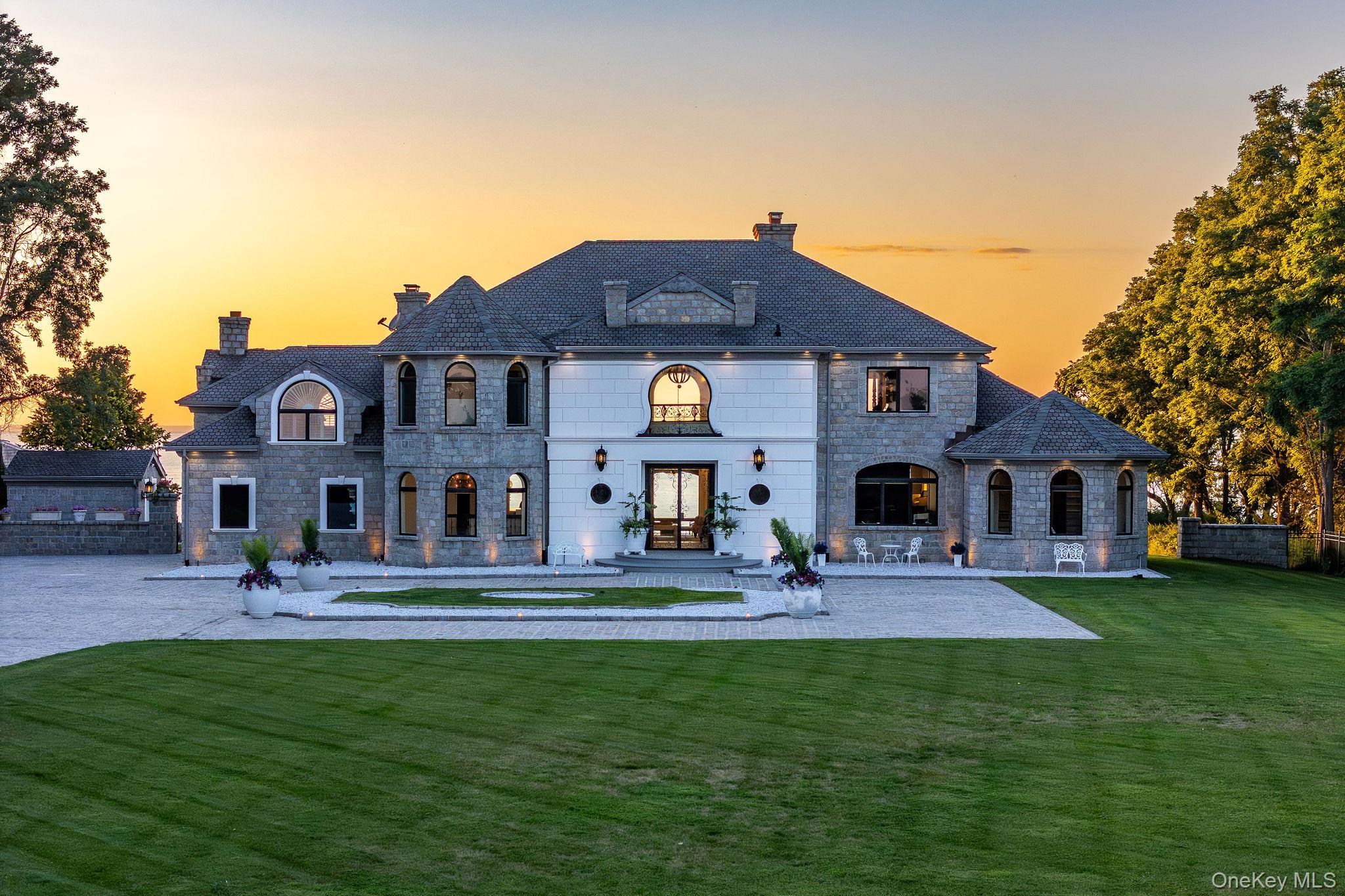 3875 Hallock Lane Mattituck, NY 11952 - Photo 41 of 50 Back of house at dusk featuring a chimney, stone siding, a yard, and a high end roof
