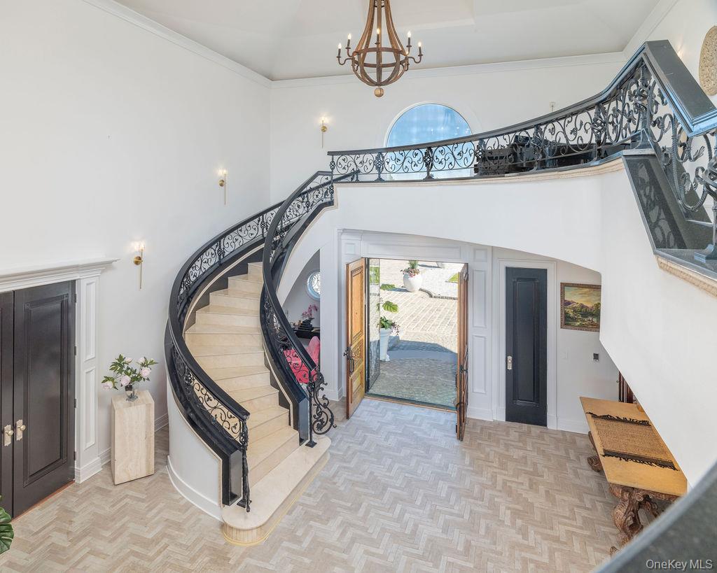 3875 Hallock Lane Mattituck, NY 11952 - Photo 9 of 50 Entrance foyer featuring stairway, arched walkways, a towering ceiling, a chandelier, and ornamental molding