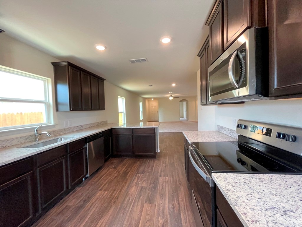 168 Allington Circle Jarrell, TX 76537 - Photo 12 of 40 a kitchen with stainless steel appliances granite countertop hardwood floor sink stove and granite counter top