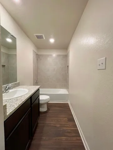 a bathroom with a granite countertop sink a toilet and shower