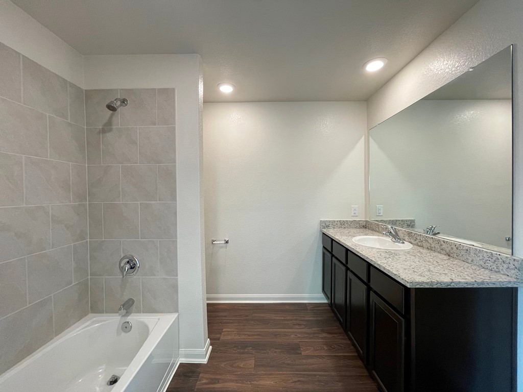 168 Allington Circle Jarrell, TX 76537 - Photo 32 of 40 a bathroom with a granite countertop sink a mirror and a bathtub