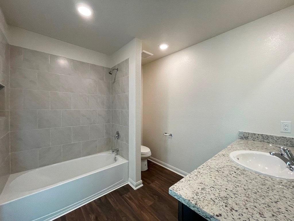 168 Allington Circle Jarrell, TX 76537 - Photo 34 of 40 a bathroom with a granite countertop sink a toilet and bathtub