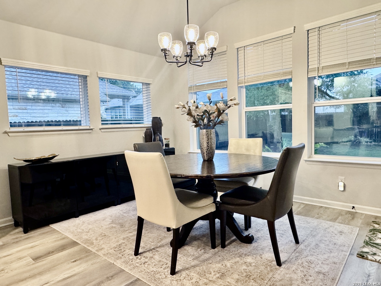 142 Willamette Way Kyle, TX 78640 - Photo 12 of 29 a dining room with wooden floor a chandelier a glass table and chairs
