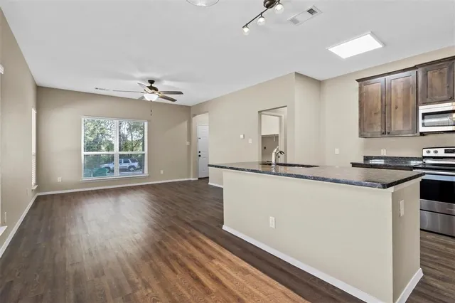 a large white kitchen with wooden floor and a window