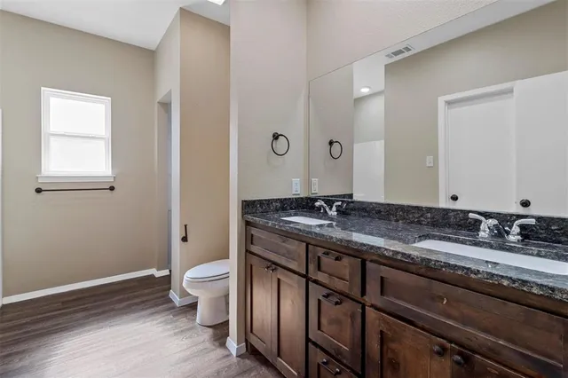 a bathroom with a granite countertop sink a toilet and a mirror