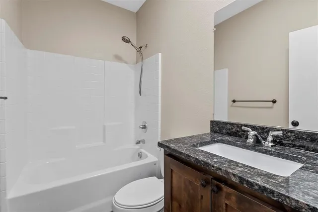 a bathroom with a granite countertop sink a toilet and shower