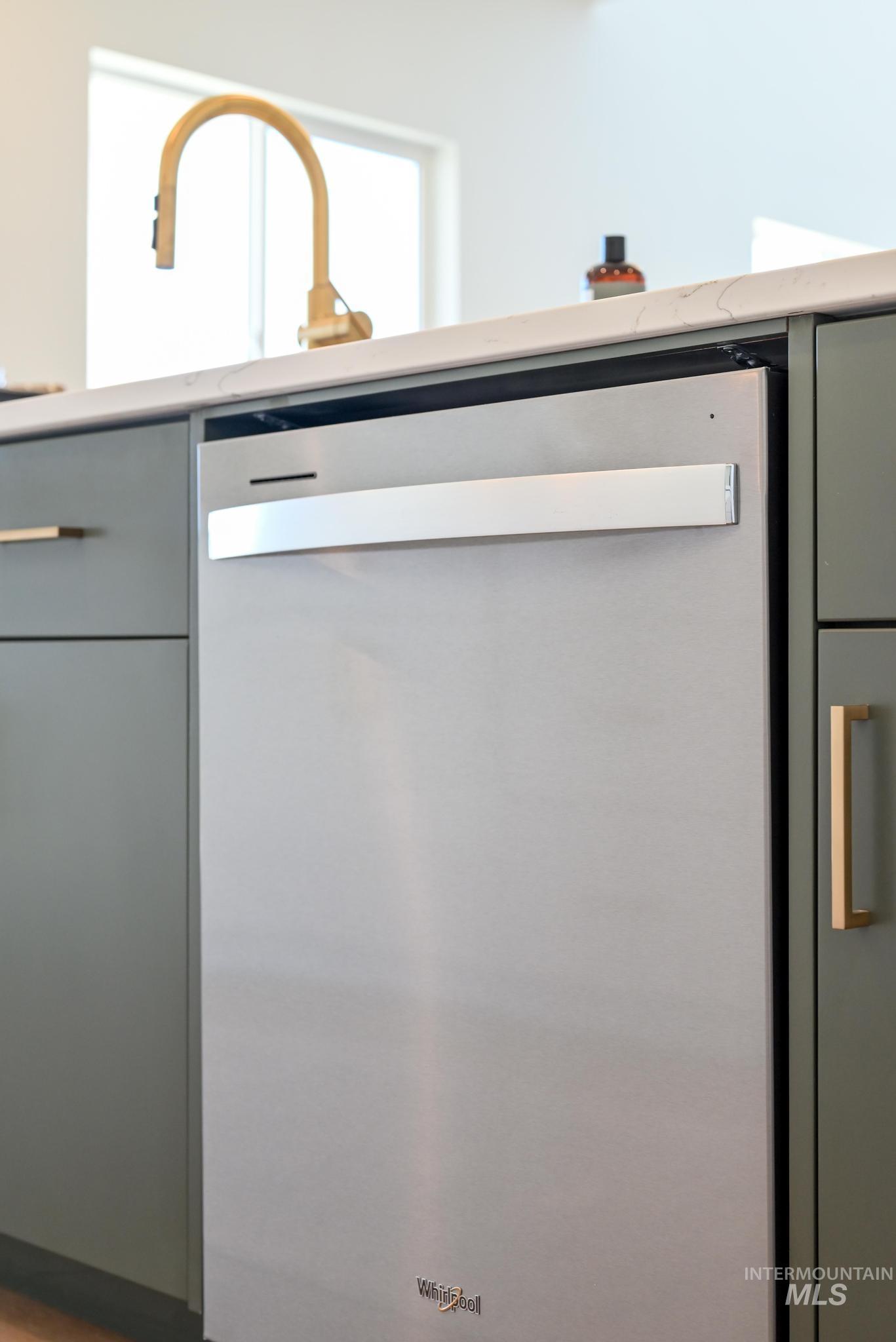 14703 Serenity Pt Street Caldwell, ID 83607 - Photo 14 of 45 Stainless steel dishwasher integrated into modern cabinetry with a light-toned countertop and gold-finish faucet