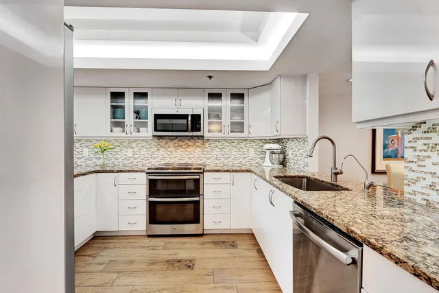 a kitchen with stainless steel appliances granite countertop a stove top oven a sink and dishwasher with wooden floor