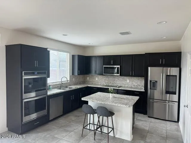 a kitchen with stainless steel appliances granite countertop a sink a stove a refrigerator and island