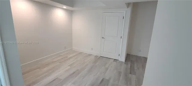 a view of a hallway with wooden floor and a bathroom