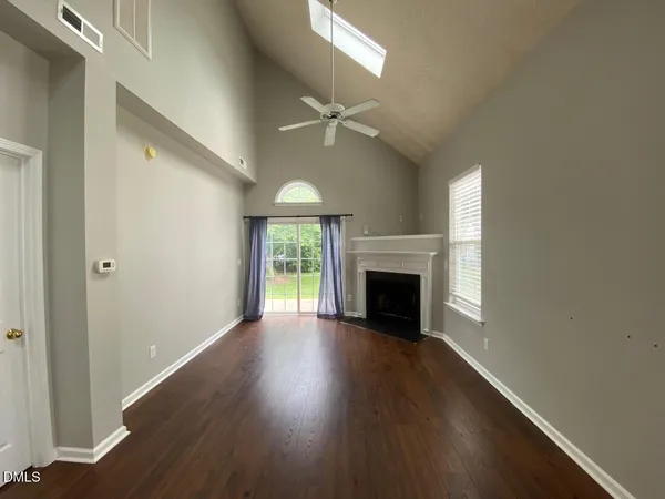 an empty room with wooden floor fireplace and windows