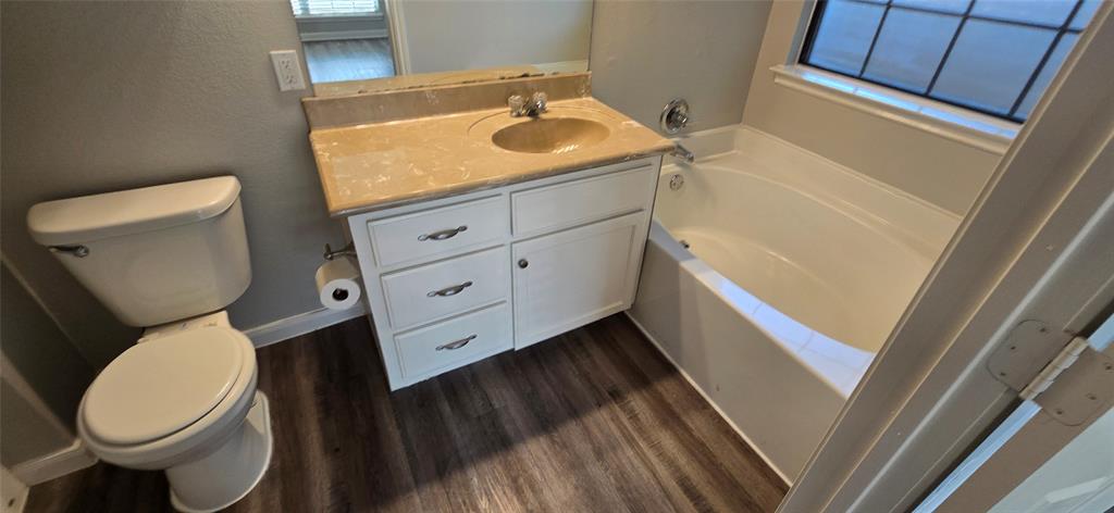 2616 South 2nd Street Waco, TX 76706 - Photo 8 of 29 Wood-finish flooring with a white vanity featuring ample storage, a built-in sink with a countertop, and a white bathtub