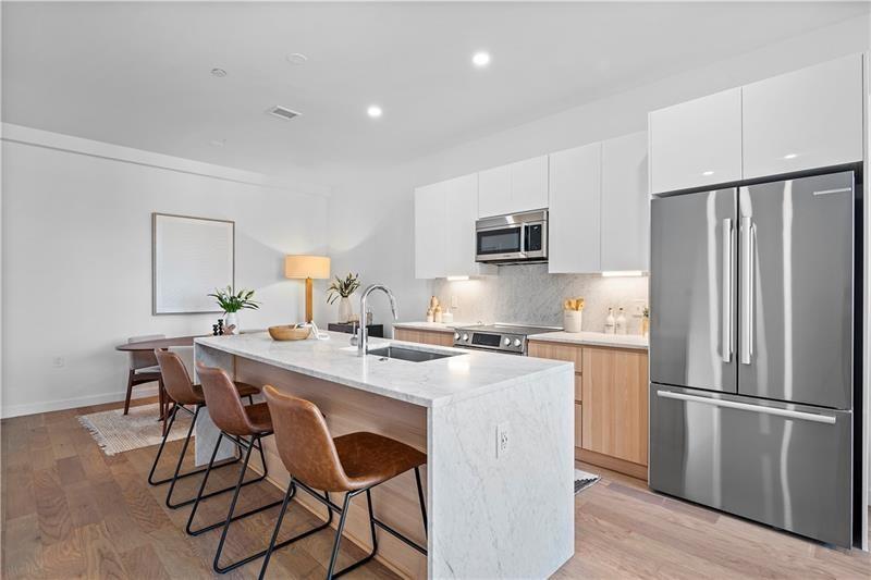 112 Burrows Street Pittsburgh, PA 15213 - Photo 5 of 13 a kitchen with stainless steel appliances a dining table chairs refrigerator and cabinets