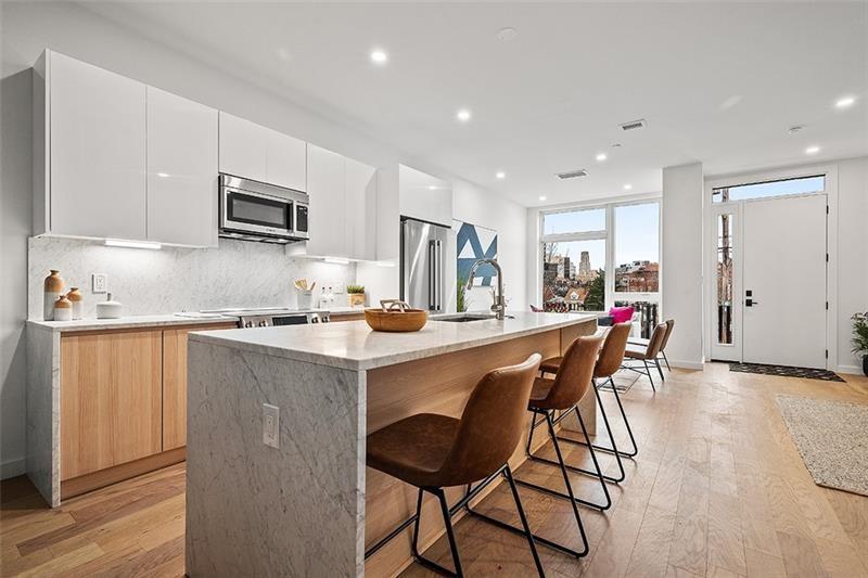 112 Burrows Street Pittsburgh, PA 15213 - Photo 7 of 13 a kitchen with stainless steel appliances a dining table chairs microwave and sink
