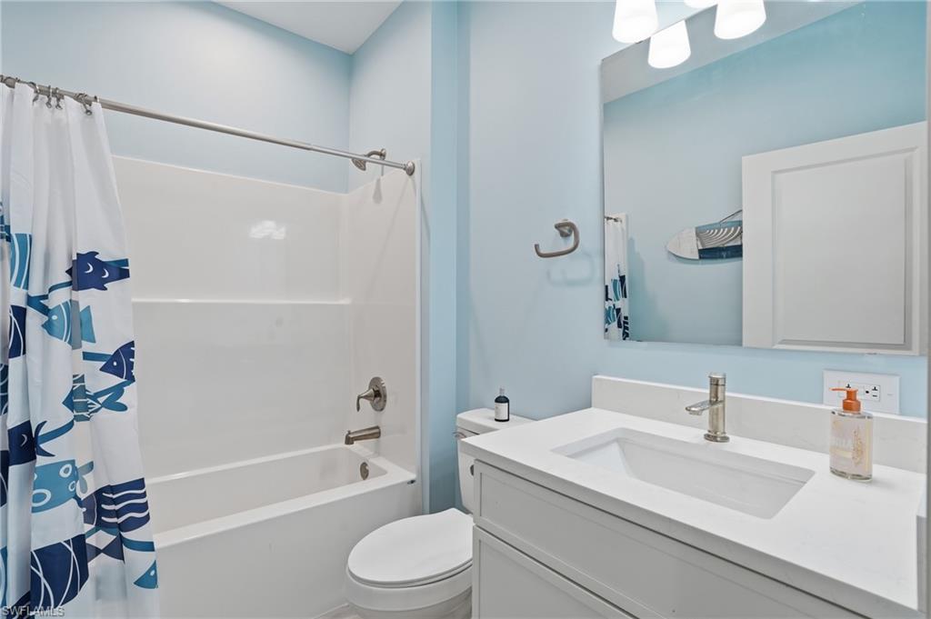 1 Fairview Boulevard Fort Myers Beach, FL 33931 - Photo 19 of 48 Full bathroom featuring a white vanity with integrated sink, brushed nickel faucet, and a wall-mounted mirror - Virtually Edited Image