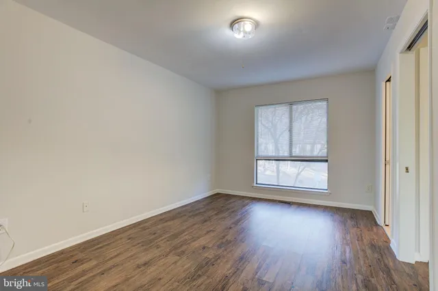 an empty room with wooden floor cabinet and windows