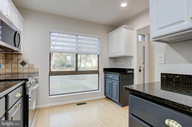 a kitchen with granite countertop a stove a sink and a microwave