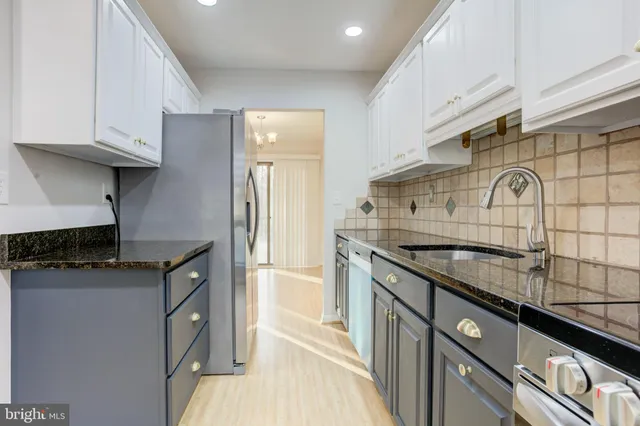 a kitchen with granite countertop a sink a stove and cabinets