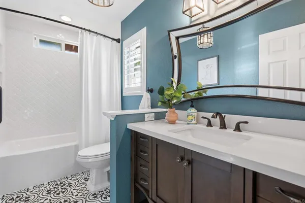 a bathroom with a granite countertop sink a toilet a mirror and shower