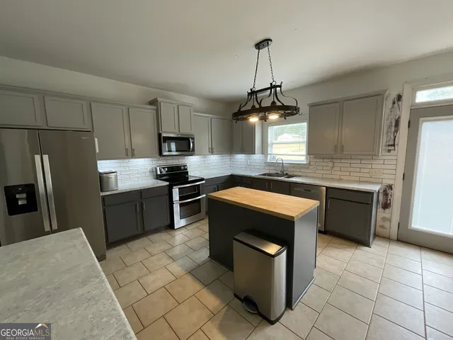 a kitchen with kitchen island granite countertop a sink counter top space appliances and cabinets