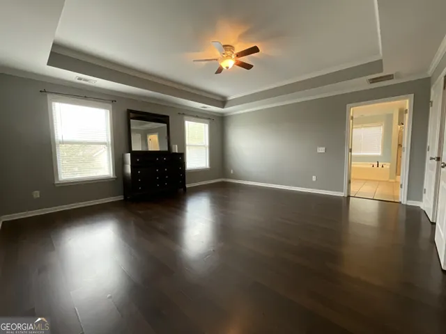 an empty room with wooden floor chandelier fan and windows