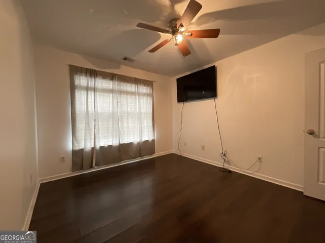 an empty room with windows and ceiling fan