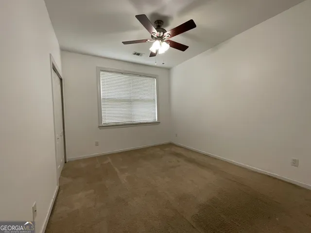 an empty room with a ceiling fan and window