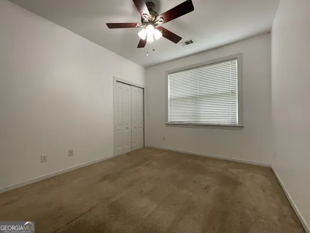 an empty room with a window and a fan