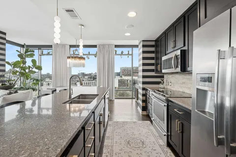 a kitchen with stainless steel appliances granite countertop a sink a stove and a refrigerator