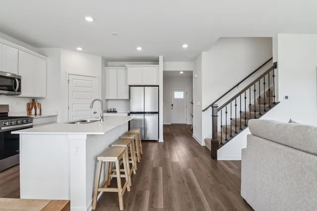 a kitchen with stainless steel appliances kitchen island wooden floors and refrigerator