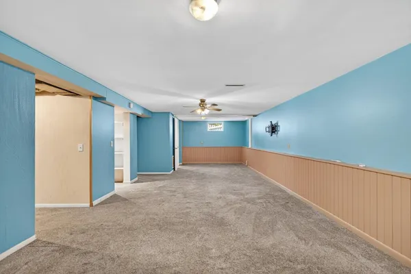 an empty room with ceiling fan and window