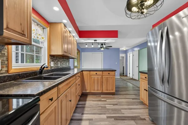 a kitchen with stainless steel appliances granite countertop a refrigerator a stove and a sink with wooden floor