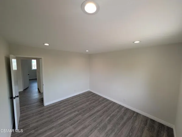 a view of an empty room with wooden floor and a bathroom