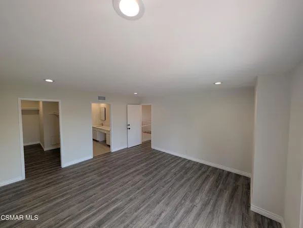 a view of an empty room with wooden floor and white walls