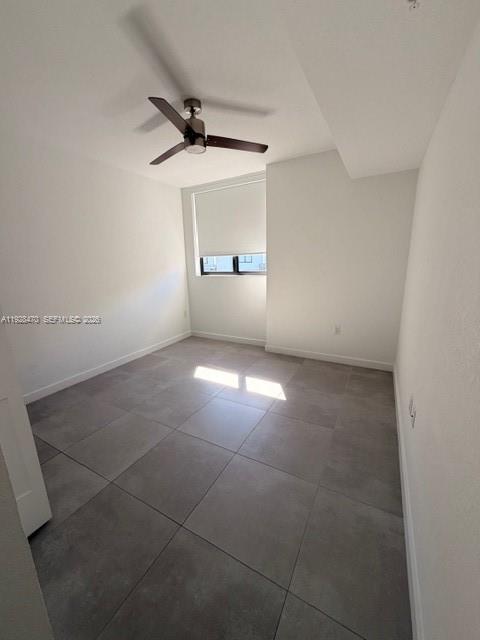 an empty room with a ceiling fan and windows