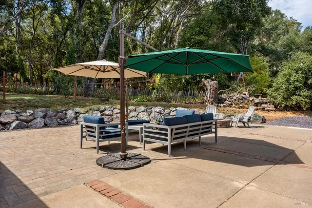 a view of a patio with chairs and tables under an umbrella