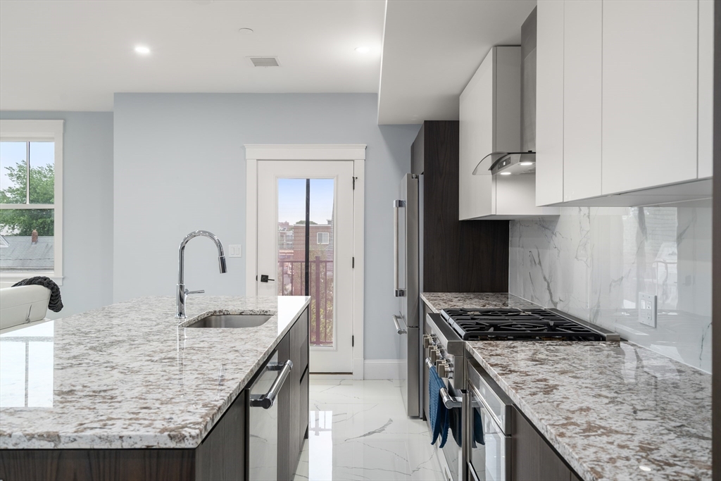 32 Pearl Street, Unit 4 Boston, MA 02125 - Photo 9 of 35 a kitchen with kitchen island granite countertop a sink and a stove