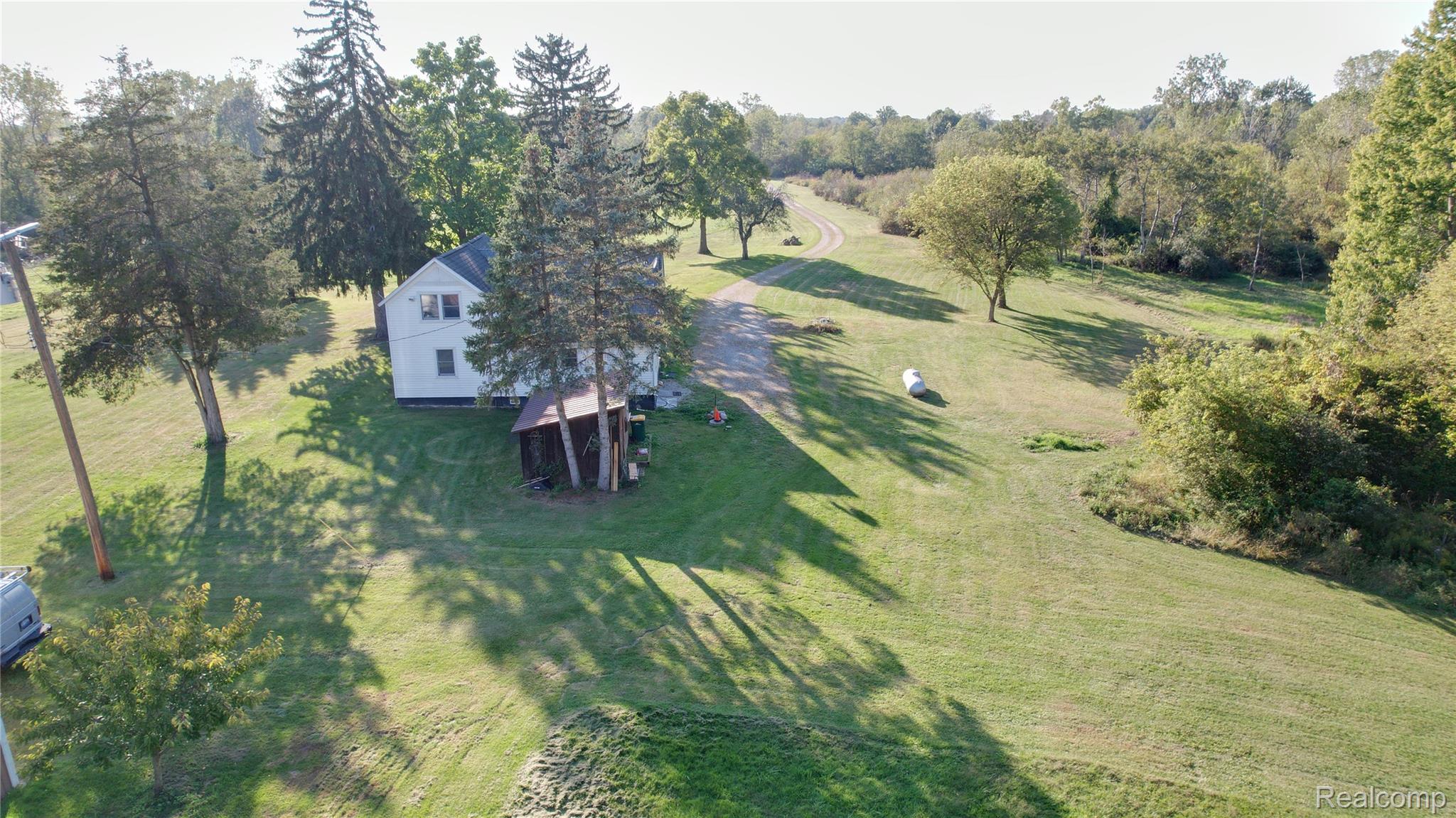 27901 Brandes Road Flat Rock, MI 48134 - Photo 6 of 38 Two-story white residence featuring a gabled roof, surrounded by mature trees and expansive green lawns