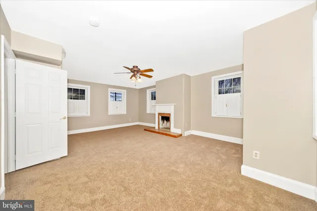 an empty room with a chandelier fan and windows